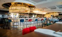 Pohled na interiér luxusní restaurace s křišťálovým lustrem nad barem
